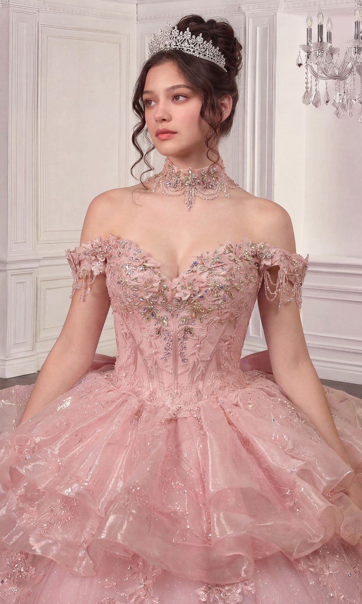 A young woman poses indoors against an ornate white paneled wall wearing the sparkling pink Quinceanera Dress 15742 By Ladivine with a detachable skirt and tiara.
